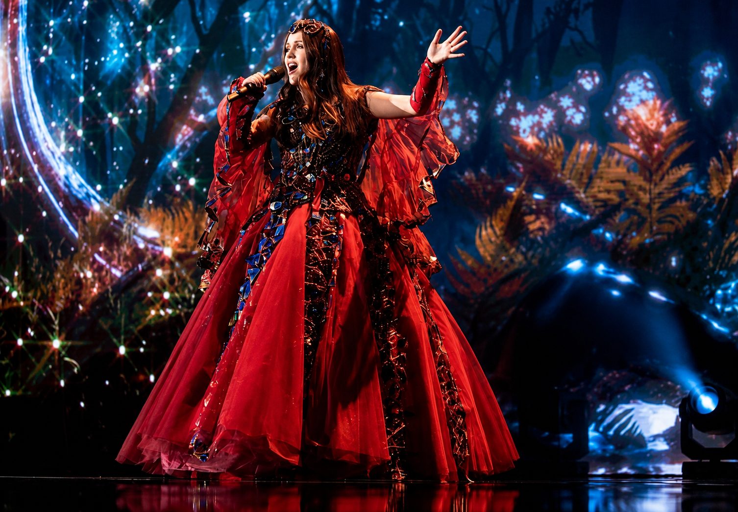 Jessica McKean performing on a large stage under coloured lights